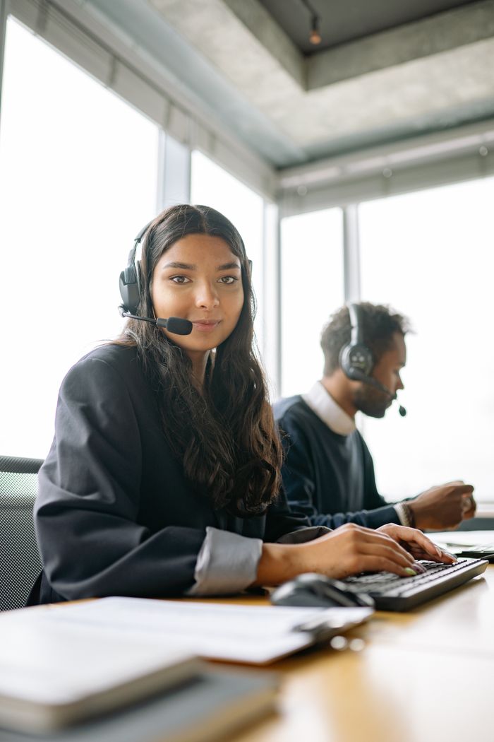 About Two customer support representatives working in a bright, modern office.